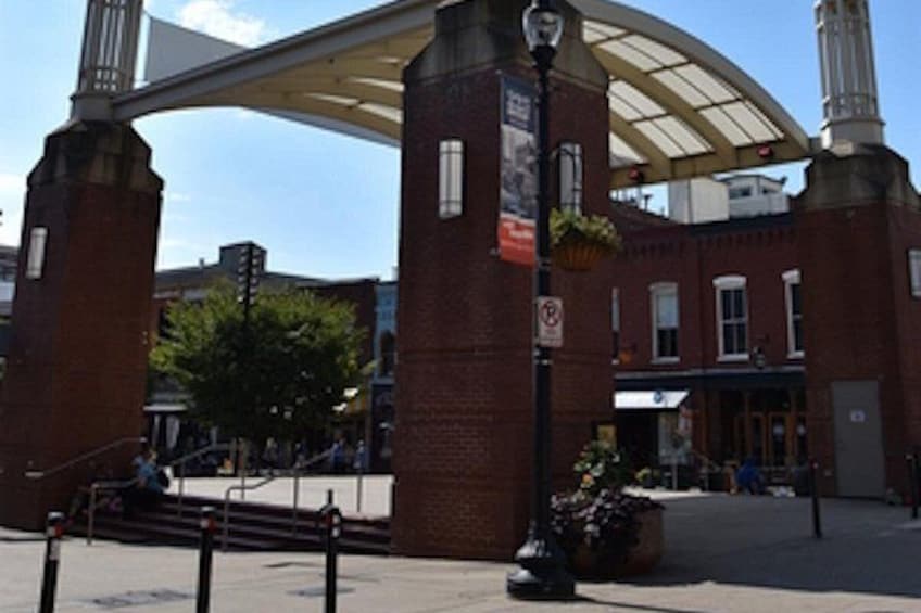 A brick building with a large arched entrance, a street lamp, and a hanging flower basket. 5