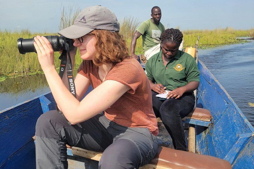 A person using a camera on a boat, another person writing, and a third person standing. 4