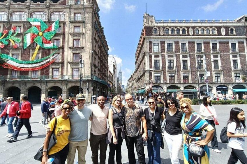 Un grupo de personas de pie en una plaza pública con edificios históricos al fondo. 5