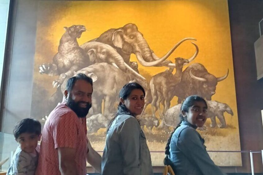 Une famille devant une fresque représentant de grands animaux. 2