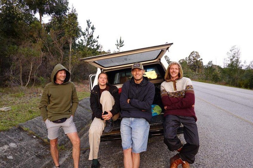 A group of people standing next to a vehicle with an open cargo area. 2