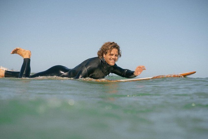 A person lying on a surfboard in the ocean. 5