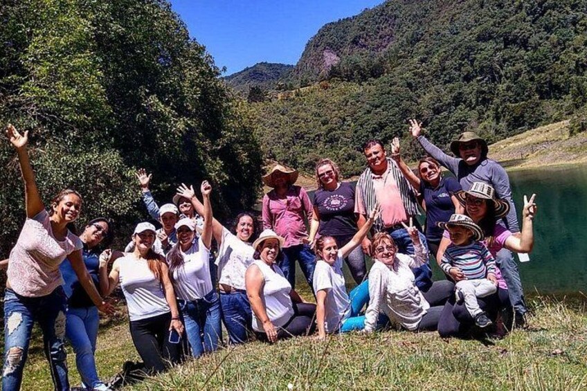 Un groupe de personnes posant à l’extérieur, avec un lac et des collines boisées en arrière-plan. 2