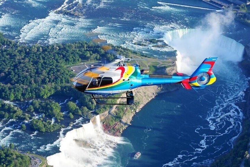 Un helicóptero colorido volando sobre una zona costera con una cascada imponente. 5