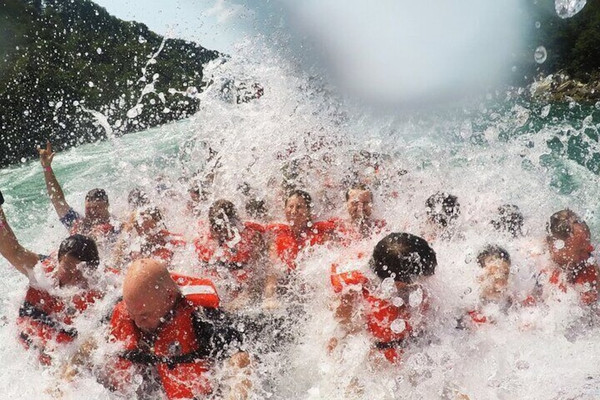 Un grupo de personas con chalecos salvavidas rojos en un cuerpo de agua, probablemente un lago o mar, con montañas al fondo. 3