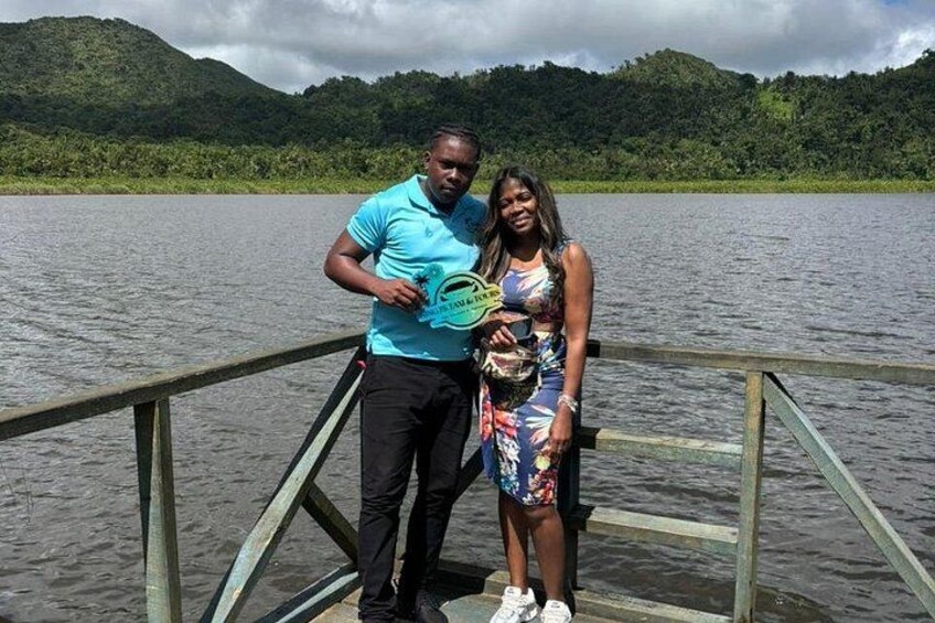Two people on a wooden dock by a lake with mountains in the background. 4