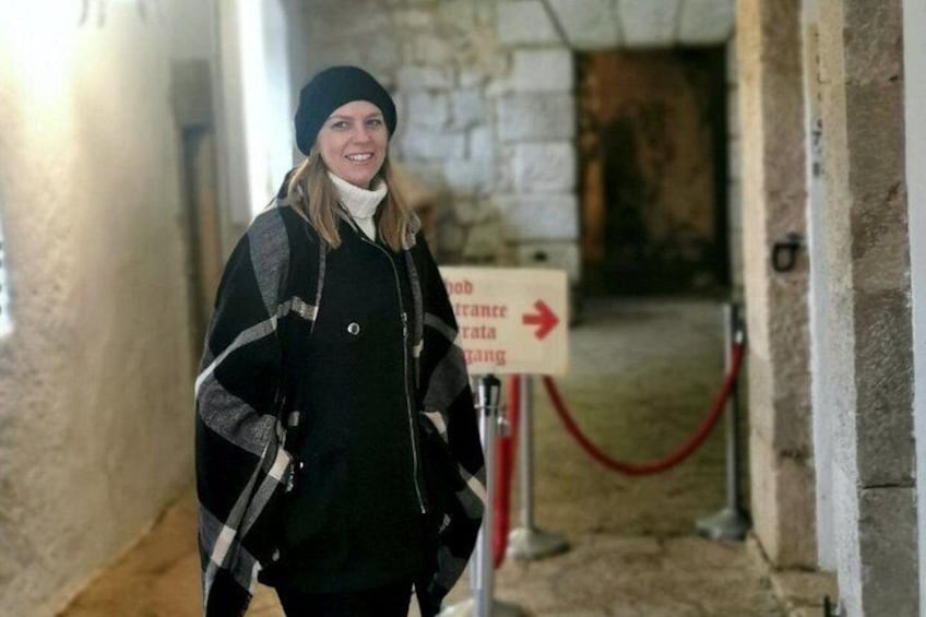 A person standing in a corridor with a sign indicating a direction to a parking area. 2