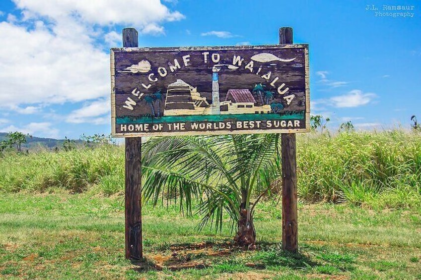 A wooden sign with 'WELCOME TO WAILUA' and 'HOME OF THE WORLDS BEST SUGAR' written on it. 4