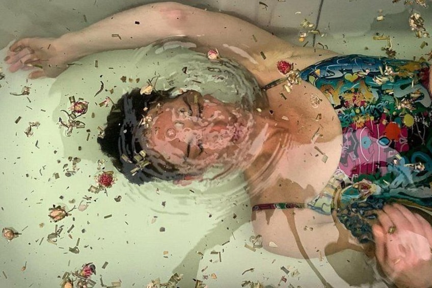 A person submerged in water with floral debris around. 1