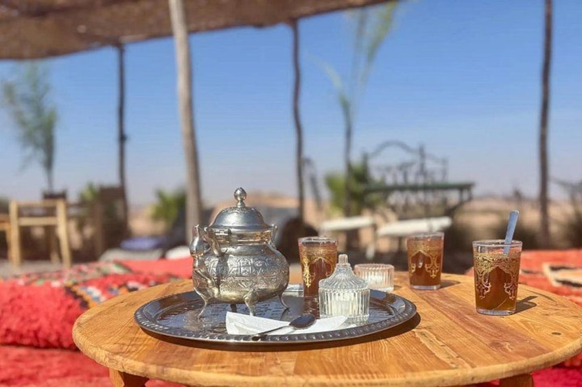 A traditional Moroccan tea set on a wooden table outdoors with a clear sky. 2