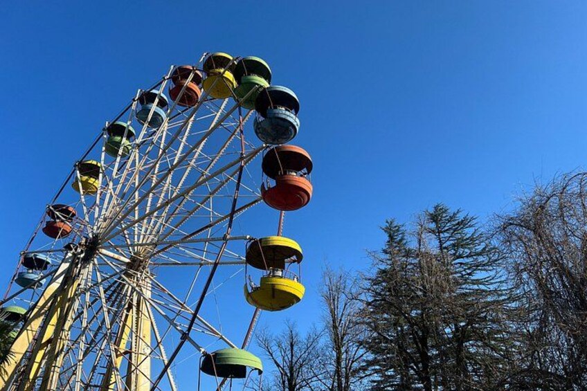 Ein Riesenrad mit bunten Gondeln vor blauem Himmel. 4