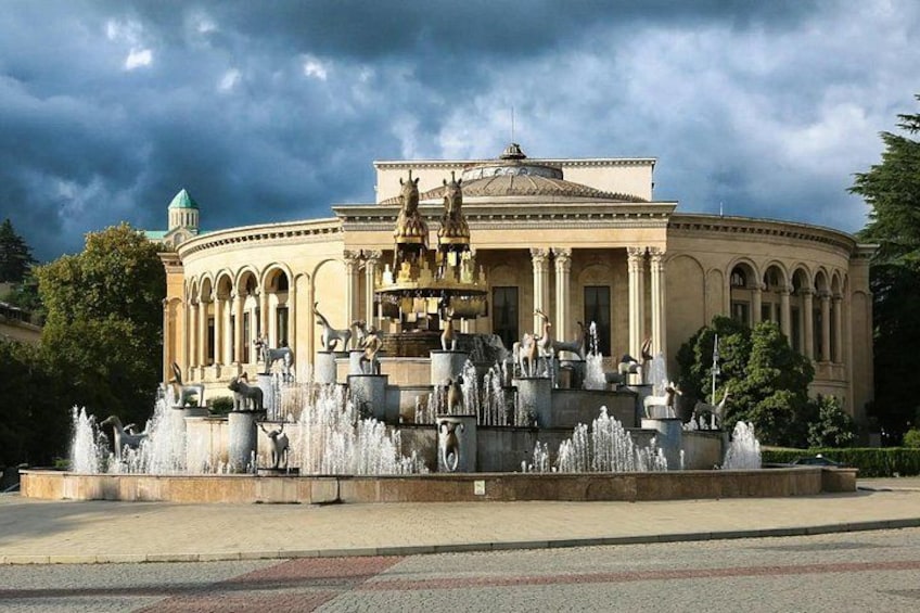 Ein klassizistisches Gebäude mit einem Brunnen davor. 1