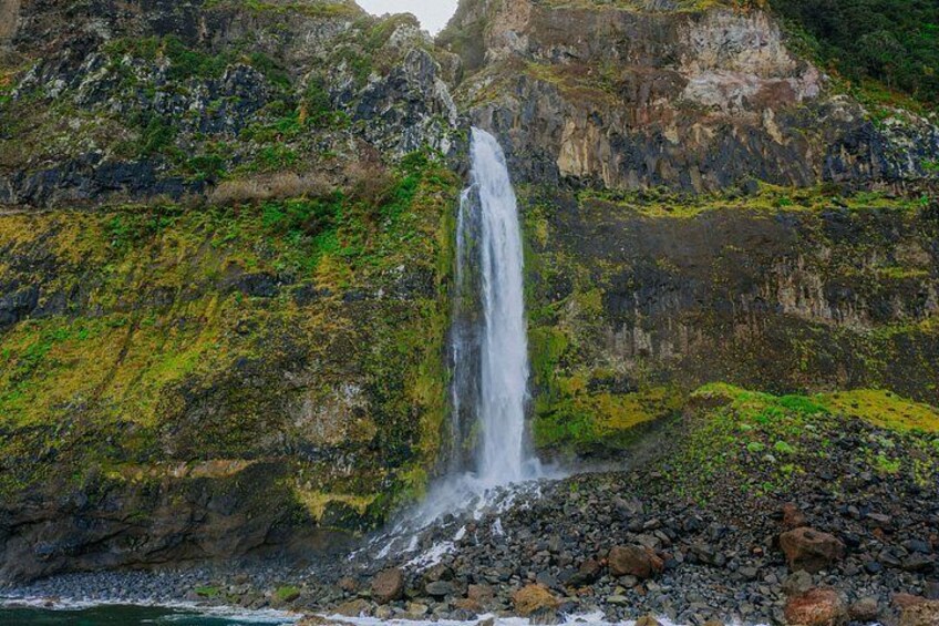 A waterfall cascading down a rocky cliff with green vegetation. 4