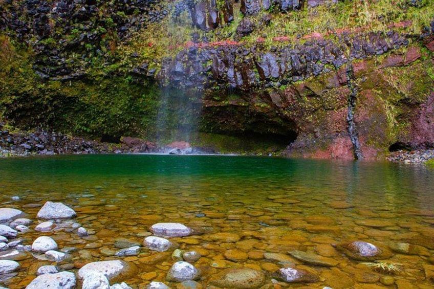 A clear stream with rocks, a waterfall, and moss-covered rocks. 2