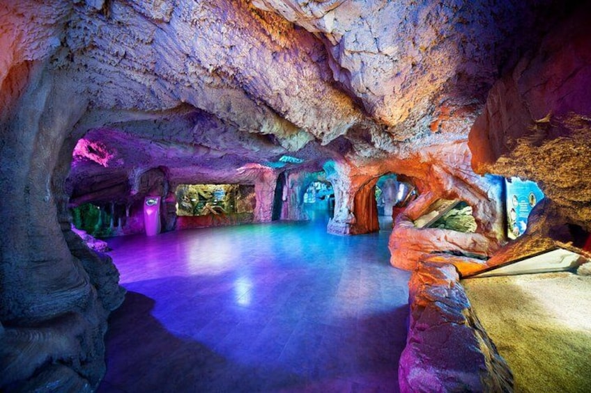 Eine unterirdische Höhle mit farbigem Licht und Felsformationen. 4