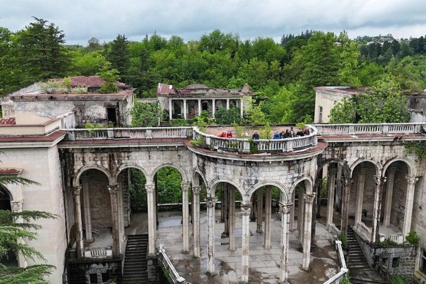 An ancient stone bridge with arches, surrounded by lush greenery and old buildings. 2