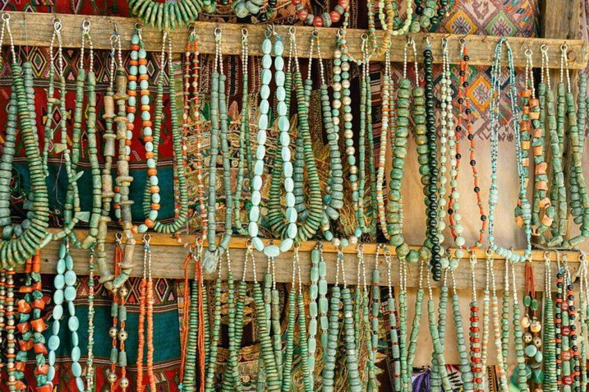 A variety of colorful beaded necklaces displayed on wooden racks. 4