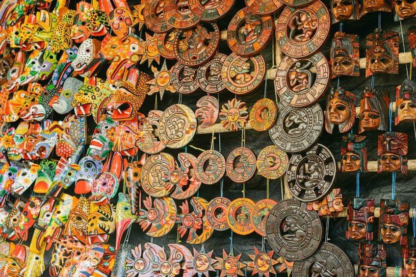 A variety of colorful masks and decorative plates hanging in a market. 5