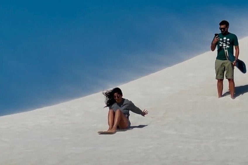 A person sitting on a sandy slope with a clear blue sky in the background. 4