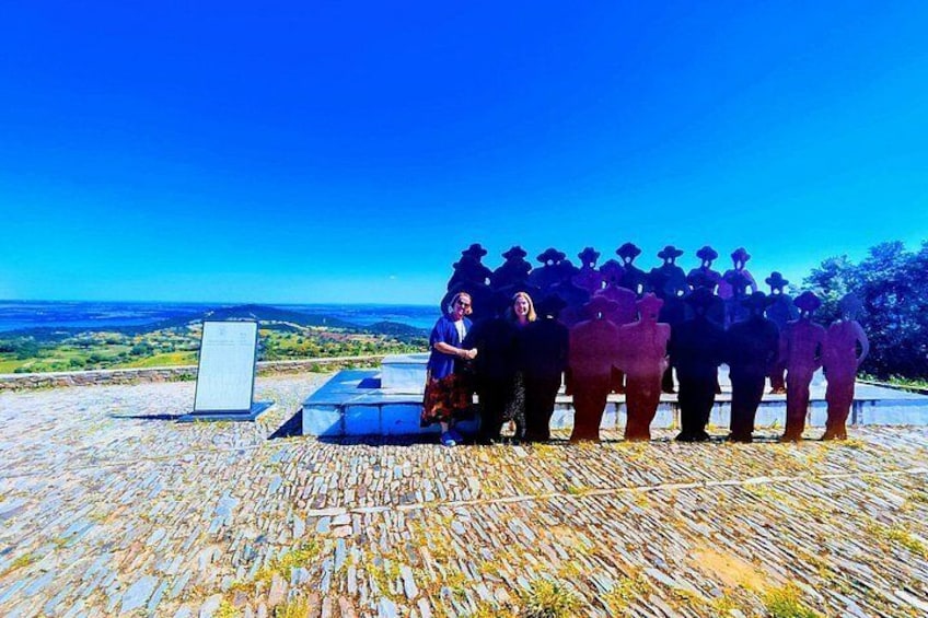 A group of people standing on a stone-paved area with a clear blue sky in the background. 5