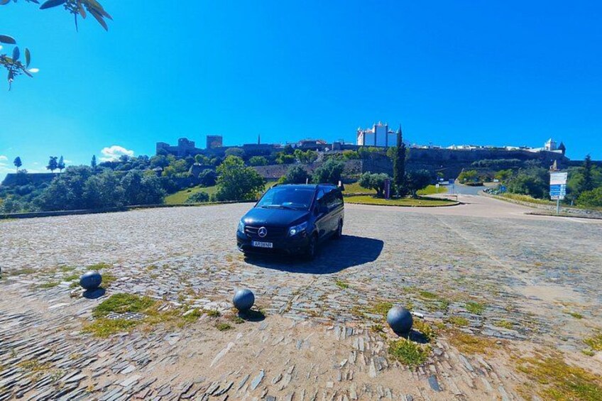 A car parked on a cobblestone path with a castle in the background. 2