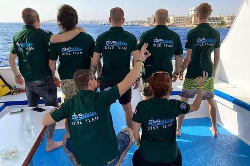 A group of people on a boat wearing green shirts with 'Dive Team' printed on the back. 3