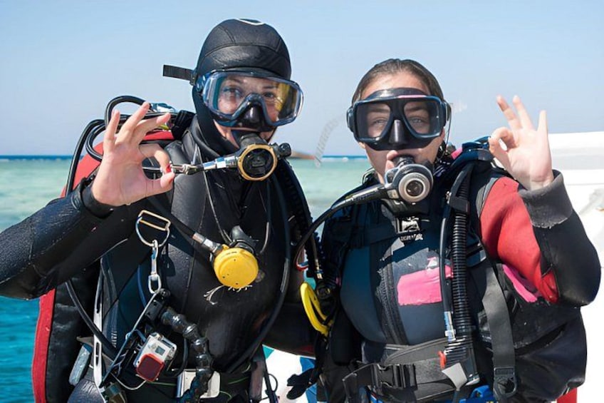 Two people scuba diving with scuba gear, including tanks and masks, in a clear blue water setting. 5