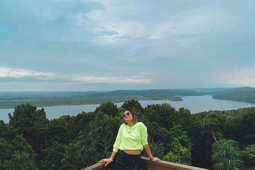 A person sitting on a wooden platform overlooking a lake surrounded by dense forest. 3
