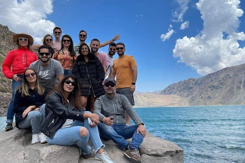 A group of people on a rocky outcrop by a body of water with mountains in the background. 2