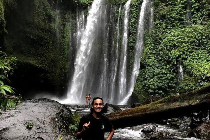 A waterfall with a person standing in front of it. 1