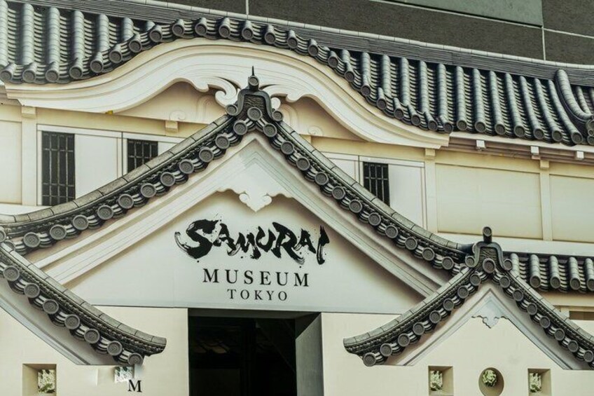 Ein Gebäude mit traditioneller japanischer Architektur, darunter gewölbte Dachziegel und ein Schild mit der Aufschrift 'Samurai Museum Tokyo'. 5
