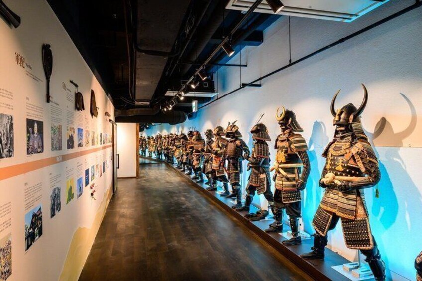 Eine Ausstellung im Museum mit einer Reihe von Samurai-Rüstungen und erläuternden Schildern. 1