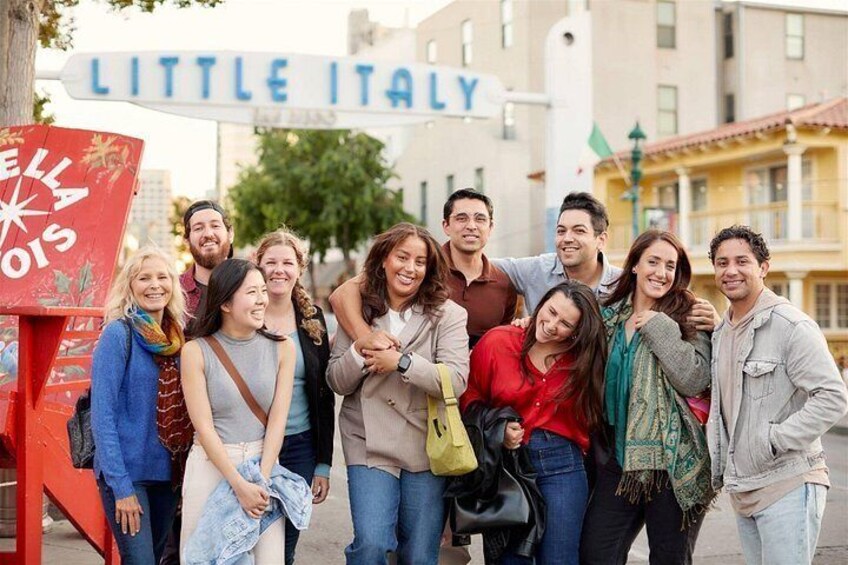 A group of people standing in front of a sign that reads 'Little Italy.' 5