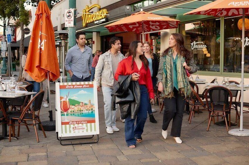 People walking outside a restaurant with outdoor seating. 3