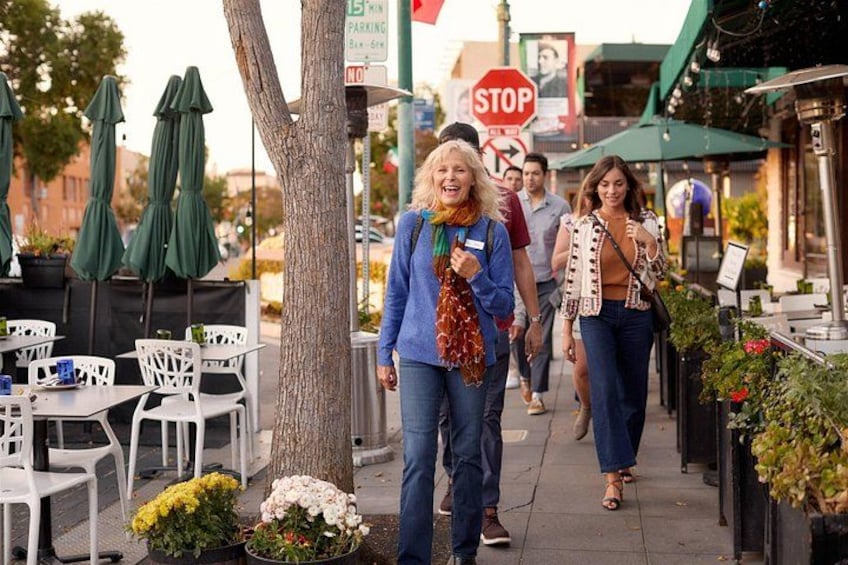 A sidewalk with outdoor seating, a tree, and a stop sign. 4