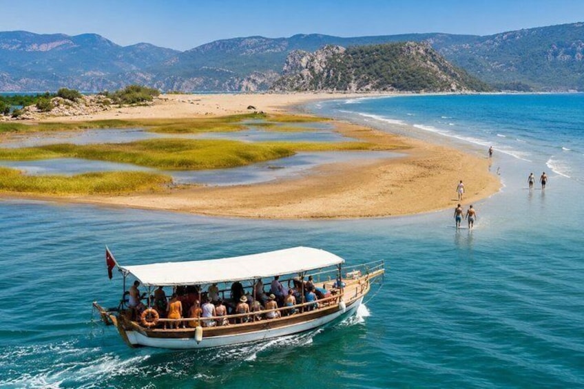 A boat with passengers on a calm sea, a sandy beach, and distant mountains. 5