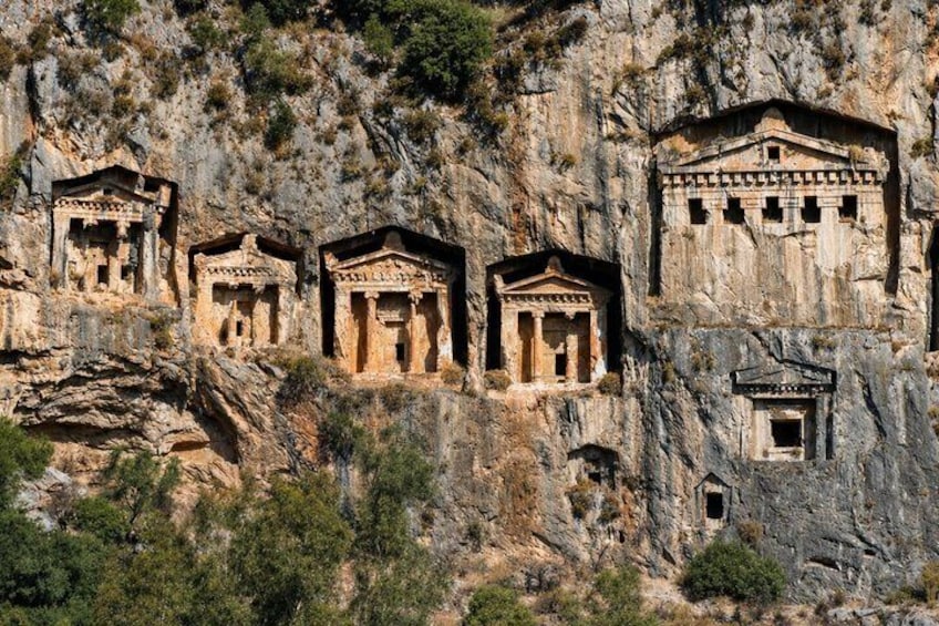 Ancient rock-cut tombs with columns and pediments carved into the cliffside. 4