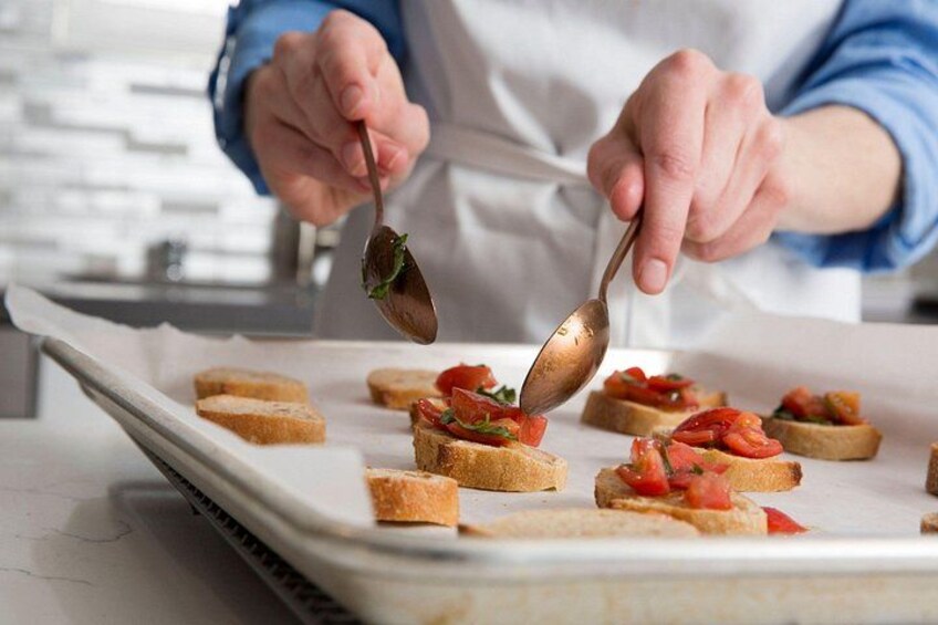 A person in a white apron preparing food on a baking sheet. 2