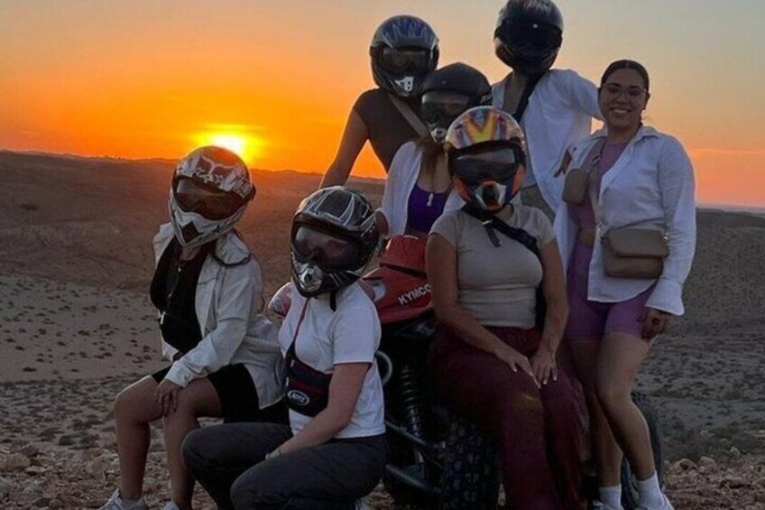 Un groupe de personnes portant des casques, assis sur une dune au coucher du soleil. 2