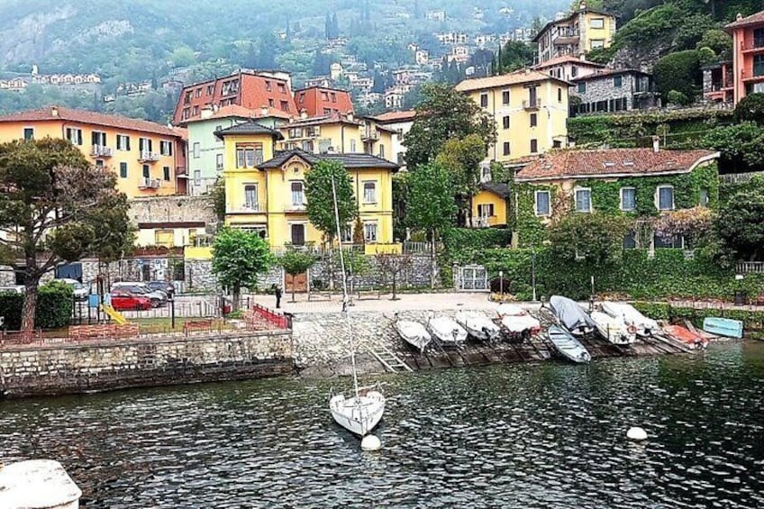 A harbor with boats docked, colorful buildings, and a mountainous backdrop. 2