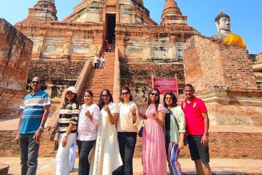 Un groupe de personnes se tient devant un temple, avec une grande statue de Bouddha. 4