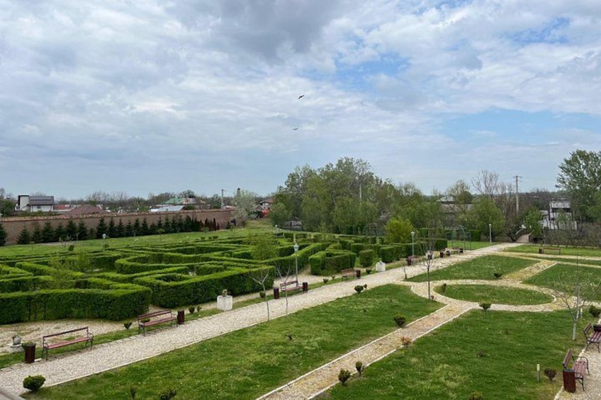 A park with neatly trimmed hedges, a gravel path, and benches. 3