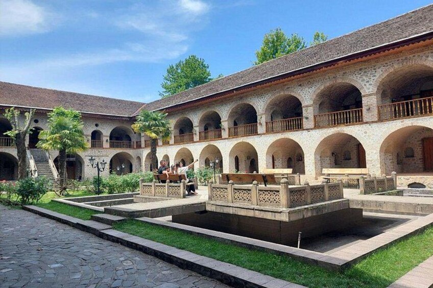 Ein Innenhof mit Brunnen, Bögen und einem Ziegeldach. 1