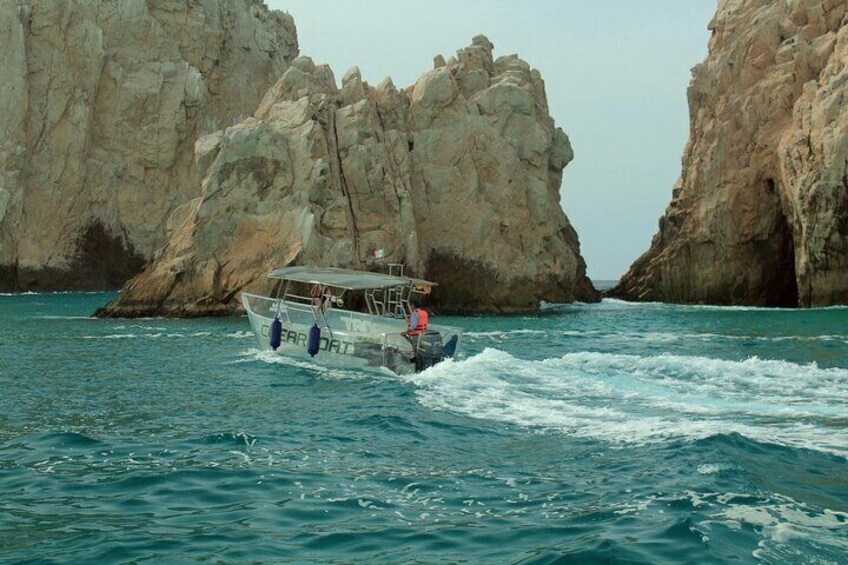 Ein Boot navigiert durch eine felsige Küstenlandschaft mit hohen Klippen. 2
