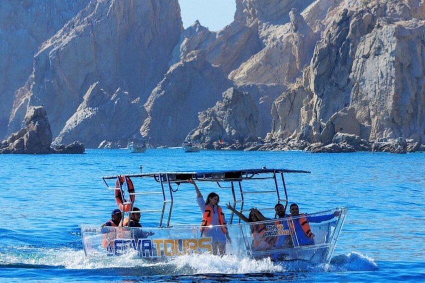A group of people on a clear water boat tour with rocky cliffs in the background. 1