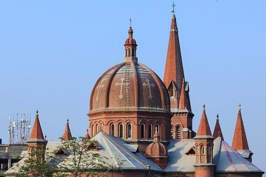 En stor kyrka byggd av rött tegel, med en framträdande kupol och flera tornspiror. 1