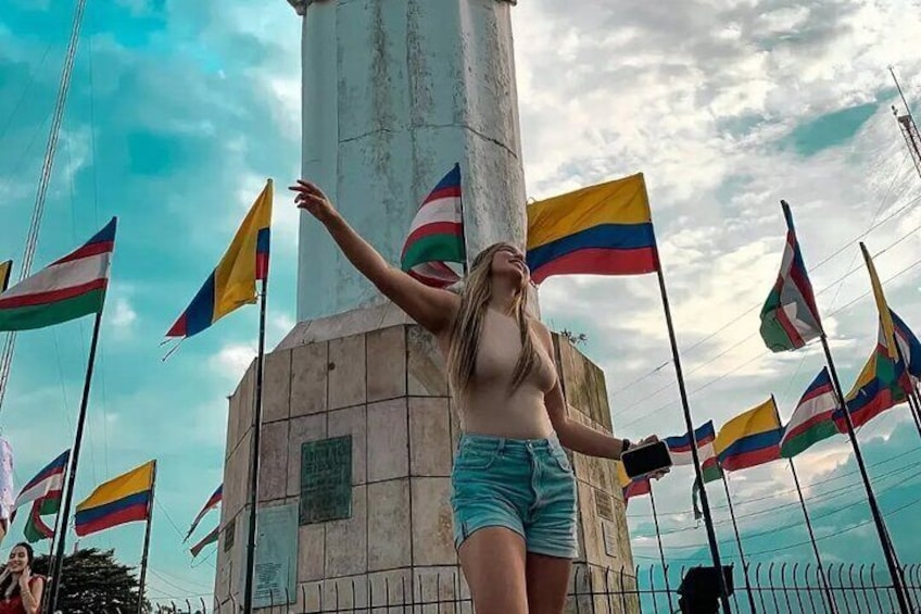 En person står foran et monument med flere flag. 1