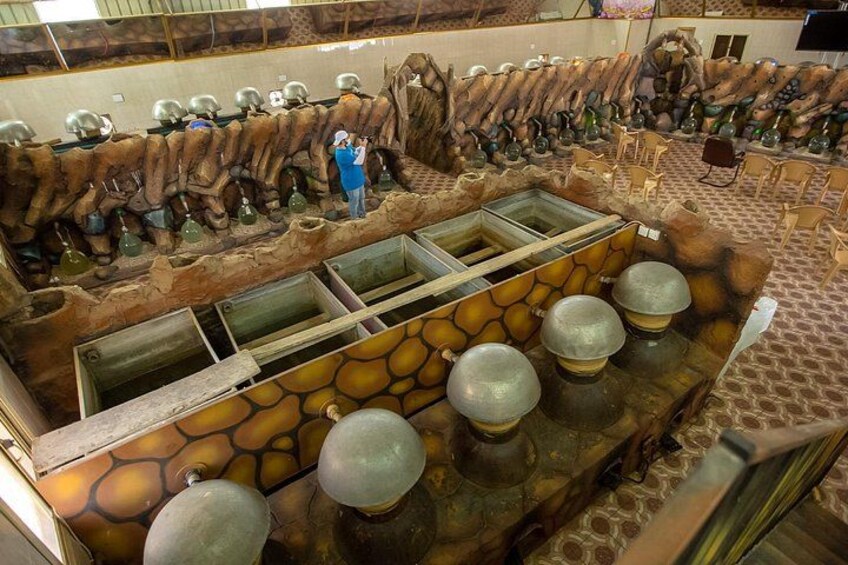 A museum exhibit with a stone wall, glass display cases, and several metal objects. 3