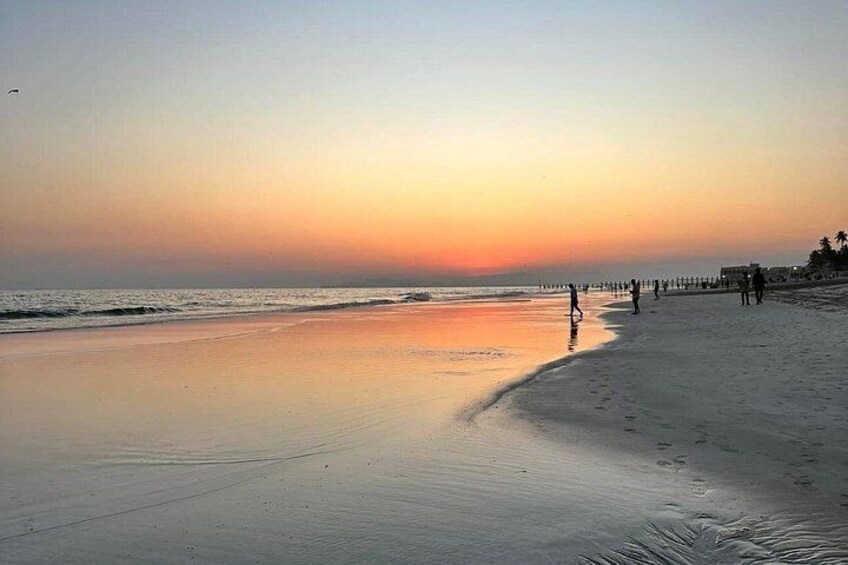 Une plage au coucher du soleil, avec des gens qui se promènent le long du rivage. 5