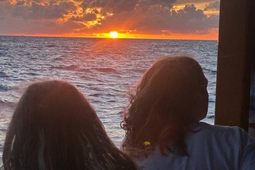 Two people looking out at a sunset over the ocean. 3